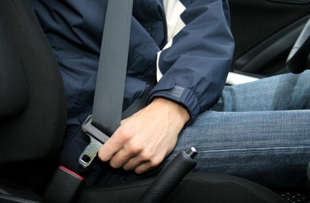 Person buckling up seatbelt.